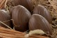 A group of chocolate eggs in a basket filled with  hay