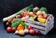 Wooden box with autumn harvest farm vegetables and root crops on black kitchen table. Healthy and organic food.